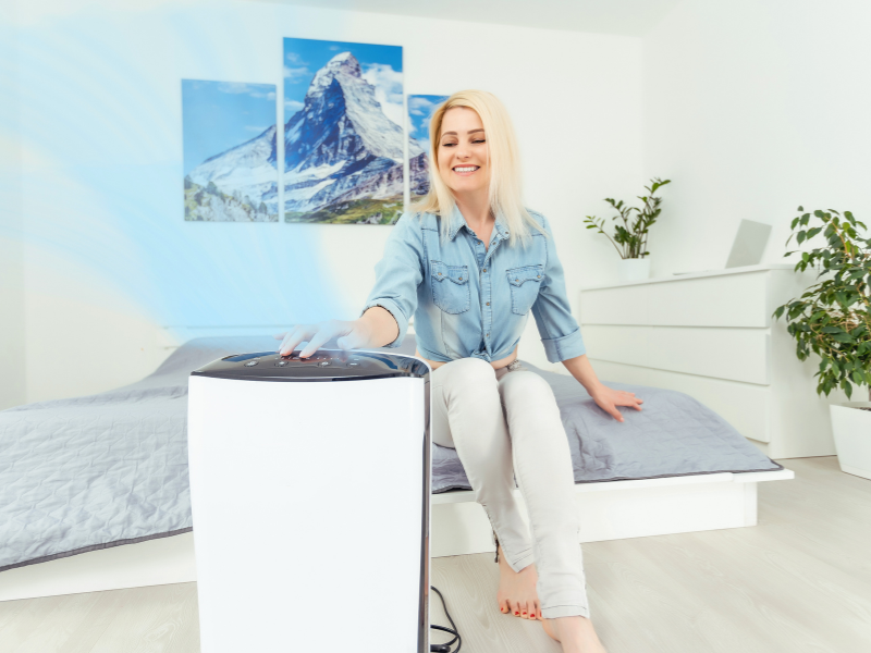 Happy woman turning on an air purifier in her small apartment